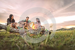 Group of travelers camping and doing picnic and playing music together. Mountain and lake background. People and lifestyle.