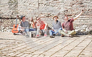 Group of trendy friends taking selfie with mobile cell phone in old historical town center outdoor - Technology mania of new