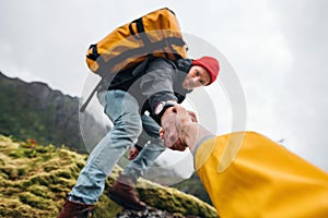 Group of two active tourist with backpack climb to rock helping each other photo
