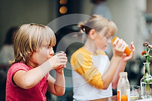 Group of two funny kids having drink in cafe