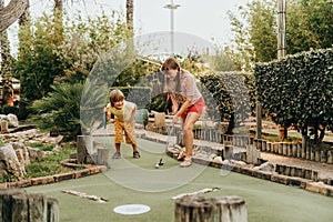 Group of two funny kids playing mini golf photo