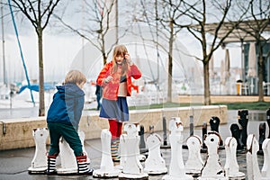 Group of two kids playing giant chess on playground