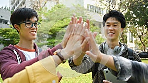Group of university friends giving high five, celebrating together. University, youth lifestyle and friendship concept