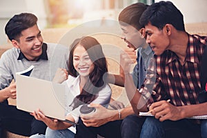 Group of university students smiling as they use laptop computer