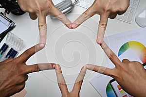 Group of unrecognizable businesspeople making star shape their fingers. Motivation, teamwork and unity concept
