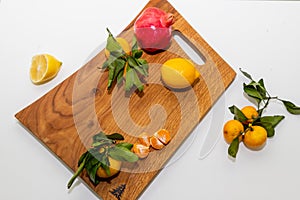 Group of various fruit consists half of tangerines, pomegranates,lemon close up fresh fruit on wooden cutting board