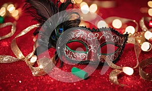 A group of Venetian or Mardi Gras masks on a dark, glittery surface with a bokeh light effect in the background.