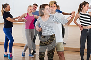 Group of vigorous teen dancing tango in dance studio