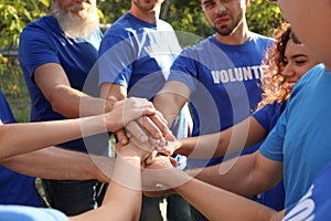 Group of volunteers joining hands together outdoors