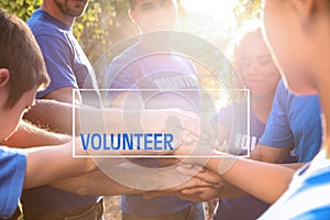 Group of volunteers joining hands together outdoors