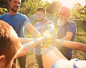 Group of volunteers joining hands together on sunny day