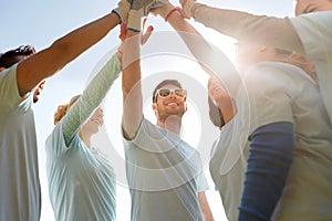 Group of volunteers making high five outdoors