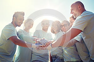 Group of volunteers putting hands on top outdoors