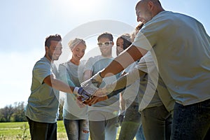 Group of volunteers putting hands on top outdoors