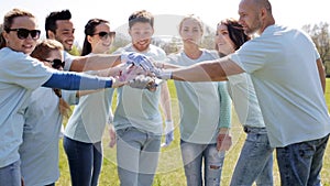 Group of volunteers putting hands on top in park