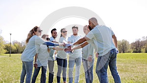 Group of volunteers putting hands on top in park