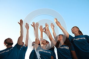 Group of volunteers raising hands outdoors