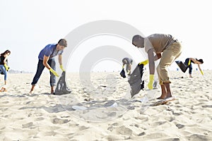 Group Of Volunteers Tidying Up Rubbish On Beach photo