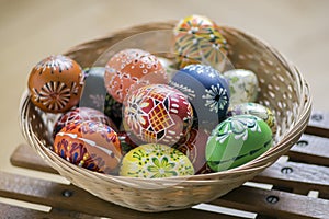 Group of wax painted Easter eggs in light brown wicker basket
