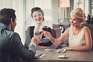 Group of wealthy people clinking glasses of red wine in restaurant