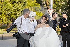 A group of wedding photographers on the streets of Budapest is holding a photo session for a couple of newlyweds.