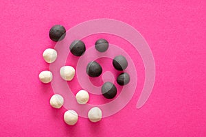 Group of white and black plasticine balls on pink vibrant background. Concepts of racism, group separated representing intolerance