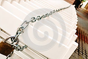 Group of white chairs tied with a chain and padlock