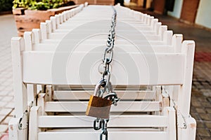 Group of white chairs tied with a chain and padlock
