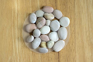 Group of white, grey and light brown stones on wooden background, pebbles beach, circle mandala shape