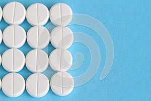 Group of white round pills on a blue background