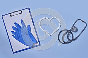 Group of white round pills forms heart figure from white pills, notebook, blue gloves and stethoscopen on blue