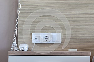 Group of white sockets, european electrical outlet and switch on a wall and telephone for contacting the reception on the bedside