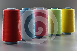 Group of whole haberdashery item colorful thread spools on grey surface