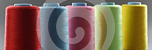 Group of whole haberdashery item colorful thread spools on grey surface