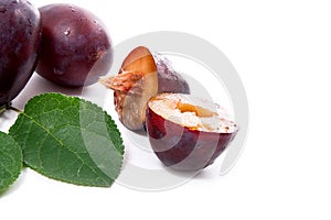 Group of whole and half of ripe plums with leaf isolated on a white background