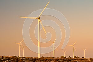 Group of wind power station for renewable electric energy production. Windmills on the sunset. High wind turbines for generation