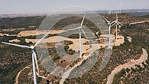 Group of wind turbines at a wind farm on a hill with some fields in summer. Ecology concept