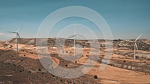 Group windmills rotate in yellow desert field. Wind turbines plant. Modern electricity production