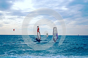 Group of windsurfers on boards in wavy sea