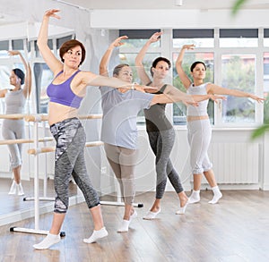 Group of women beginners practicing at ballet barre