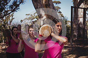 Group of women carrying a heavy wooden log during obstacle course