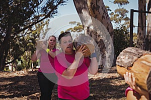 Group of women carrying a heavy wooden log during obstacle course