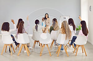 Group of women company employees sitting on chairs in a row listening to their leader.