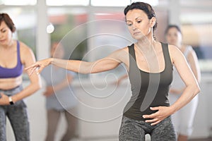 Group of women of different ages are learning various dance and ballet movements in studio