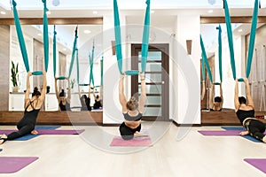 Group women doing fly yoga stretching exercises in gym. Fit and wellness lifestyle