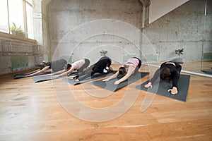 Group of women doing stretching exercise in hall.
