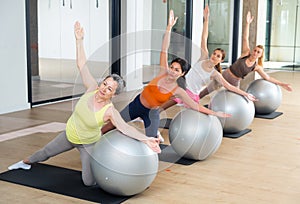 Group of women doing stretching exercises with swiss balls