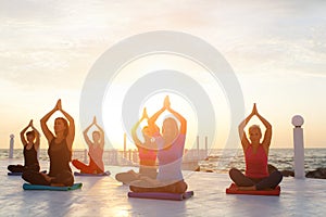 A group of women doing yoga at sunrise near the sea