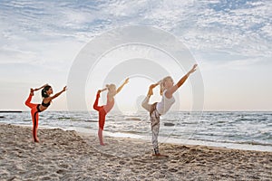 A group of women doing yoga at sunrise near the sea