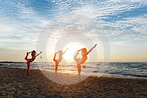 A group of women doing yoga at sunrise near the sea